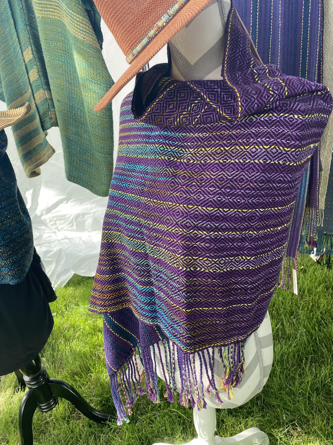 Purple diamond-pattern handwoven shawl displayed at a Montana market booth